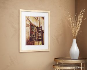 Décoration d'intérieur avec un cadre dans lequel se trouve une encre représentant les persiennes d'une maison abandonnée