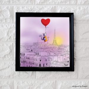 Décoration d'intérieur avec un cadre dans lequel se trouve un dessin représentant deux chats accrochés à un ballon en forme de cœur en train de survoler Paris.