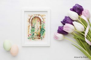 Dessin à l'encre et aquarelle d'une porte cachée derrière des roses trémières, encadré et présenté à côté de tulipes et d'œufs
