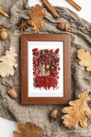 Impression laser d'une encre et aquarelle originale présentée dans un cadre et représentant une fenêtre médiévale cachée derrière des amas de feuilles rouges ©Ysae illustrations