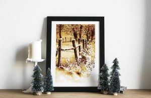 Impression laser présentée dans un cadre d'une encre originale sur chevalet représentant une barrière de piquets et de barbelé délimitant des champs enneigés dans un camaïeu ocre jaune et sépia ©Ysae illustrations